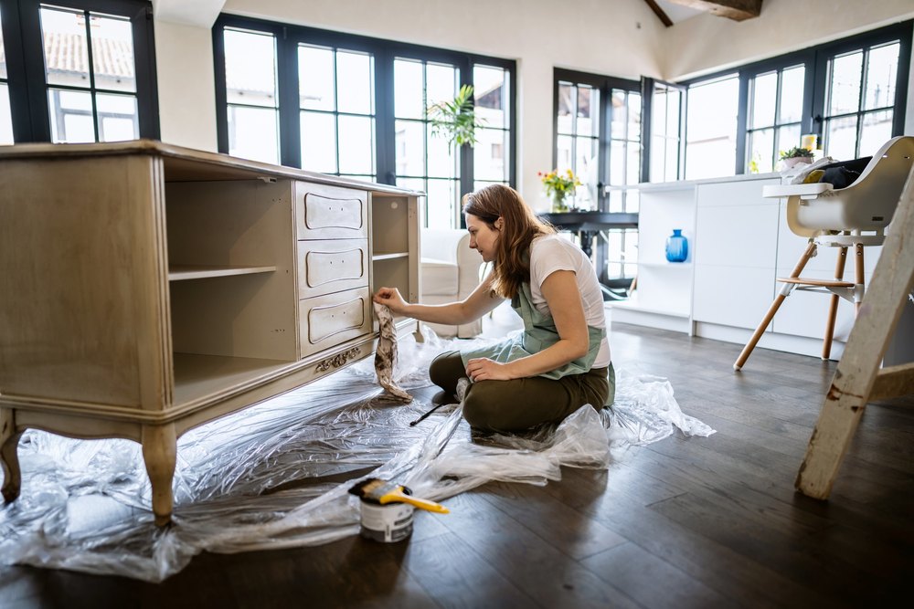 Photo of happy young woman coloring a showcase at her living room.