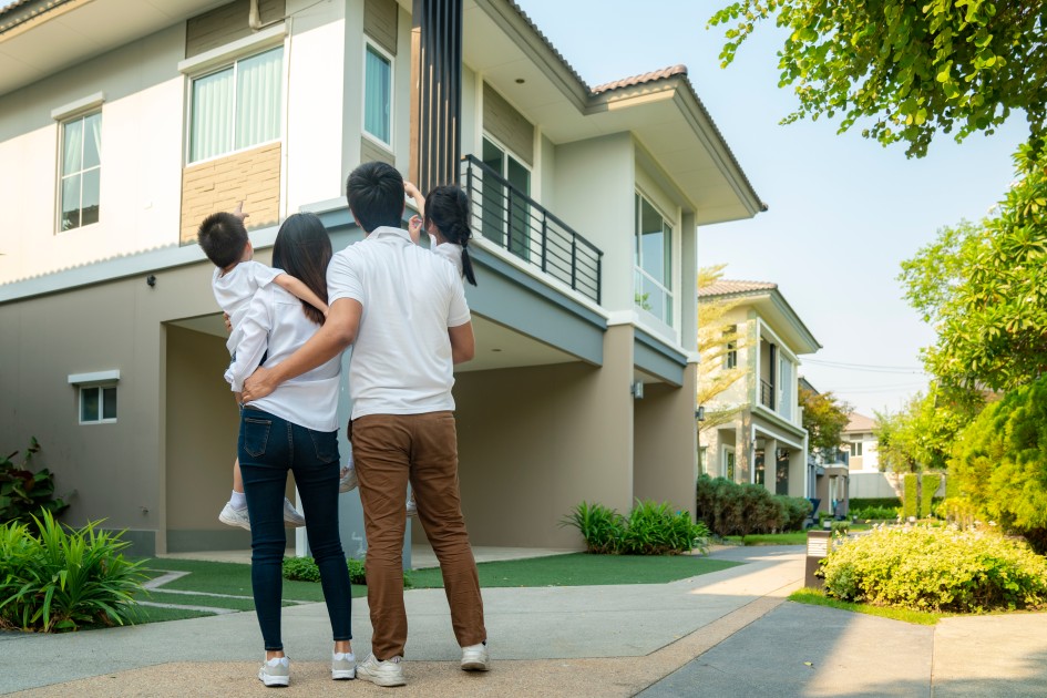 A family of four looks up at the new house they are buying in another state. 