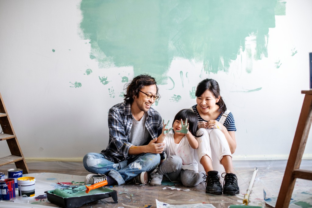 A family sits on the floor working on fixing up their house.