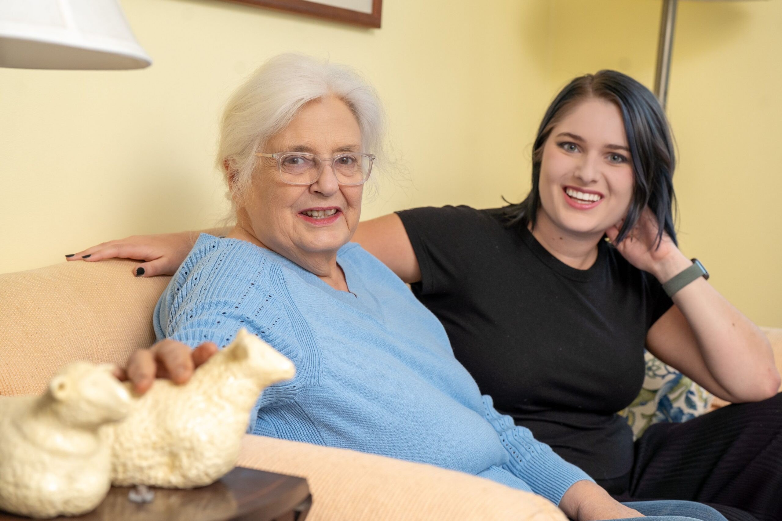 An older woman and a younger woman are sitting on a coach