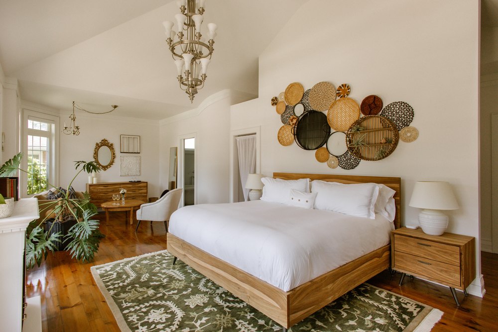 Spacious luxury bedroom suite showcasing a king bed, a unique woven basket wall installation, and a connected sitting area.