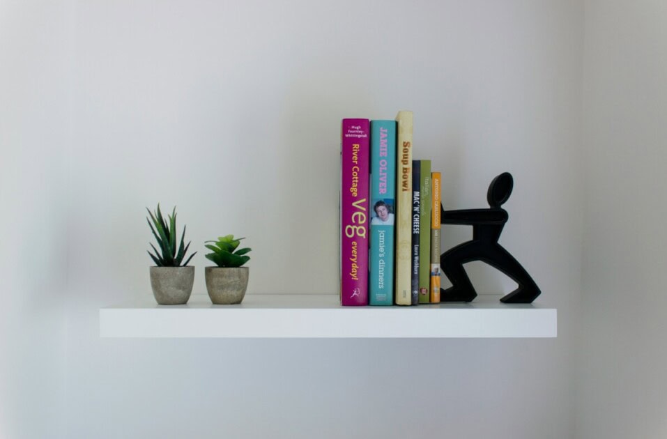 A floating shelf holding books and plants