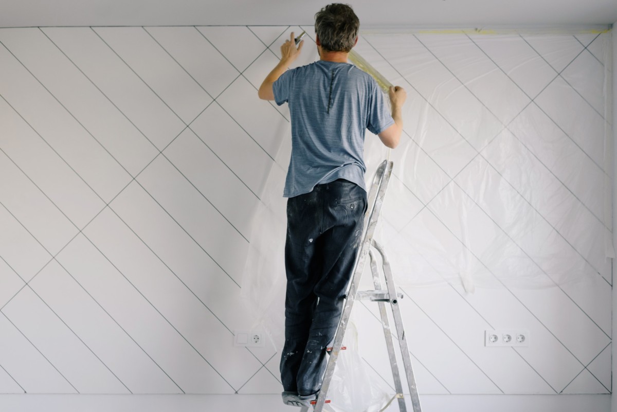 contractor standing on ladder taking measurements