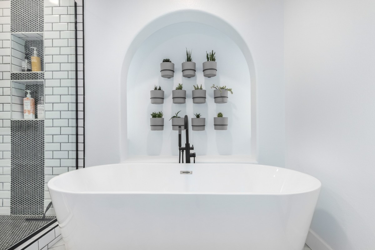bathroom design with soaking tub with a plant wall