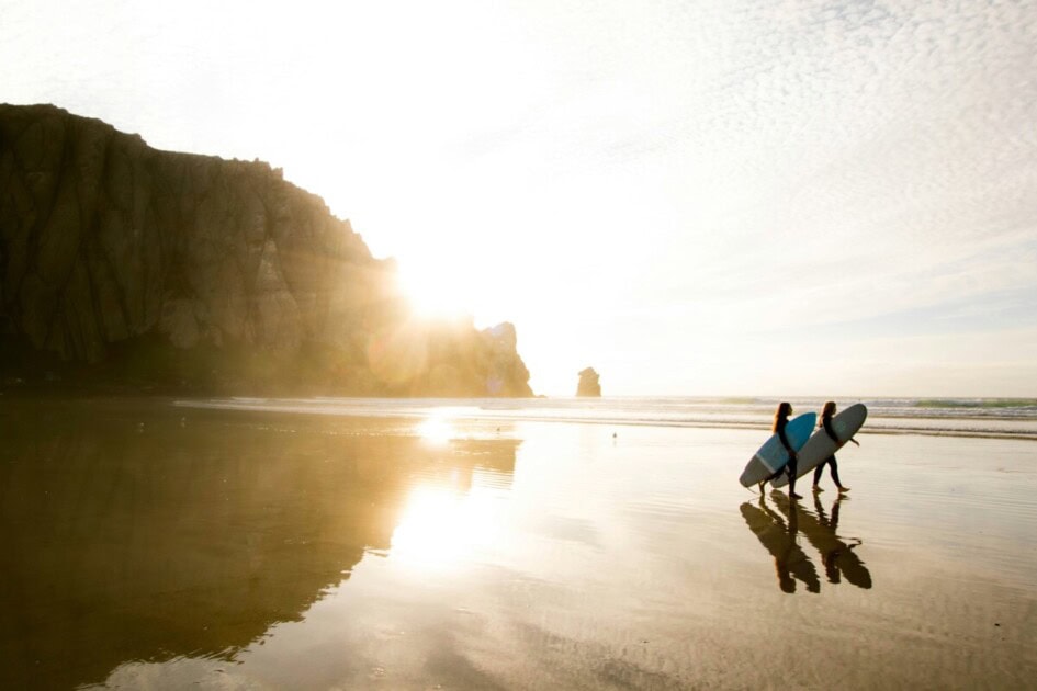 Two female surfers walking on Morro Bay while the sun shines, a summer thing to do in San Luis Obispo