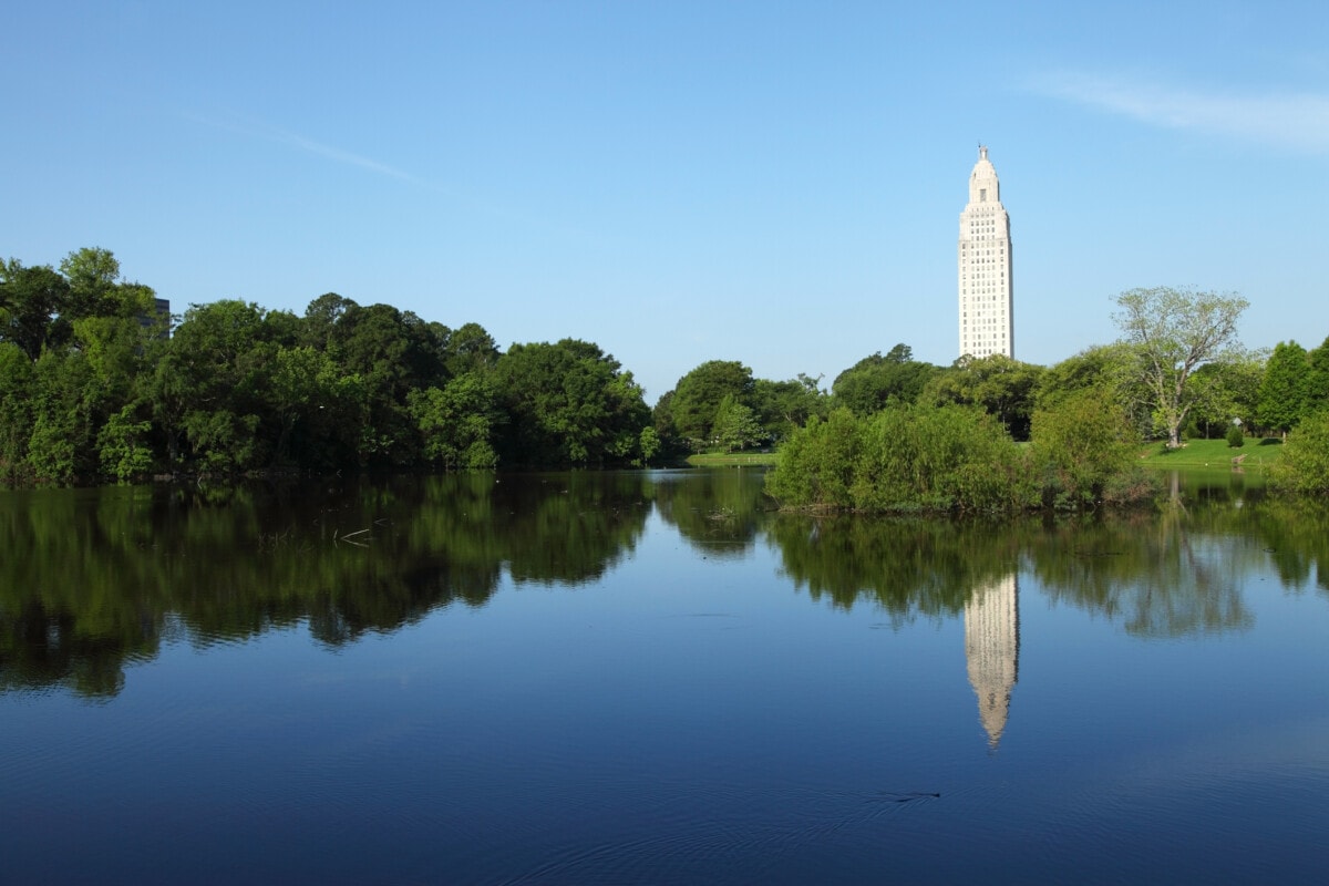 Louisiana State Capitol reflection on a small pond during the day. Louisiana State Capitol is located in downtown Baton Rouge. Baton Rouge is the second largest city in louisiana located on the banks of the Mississippi River. Baton Rouge is known for its Southern lifestyle, historic sites, bar and restaurant environment