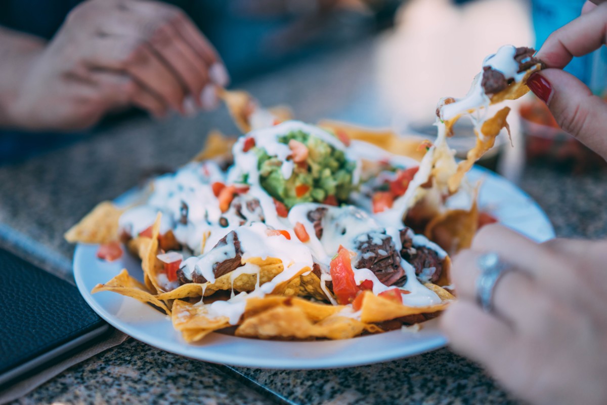 three people sharing nachos at a table