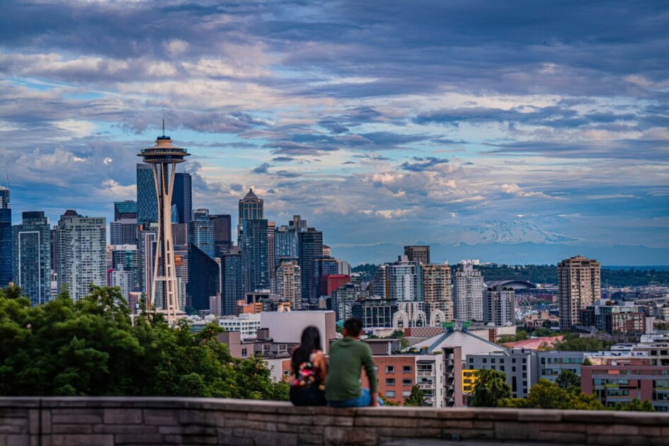 couple sits together looking at the Seattle skyline at Kerry Park