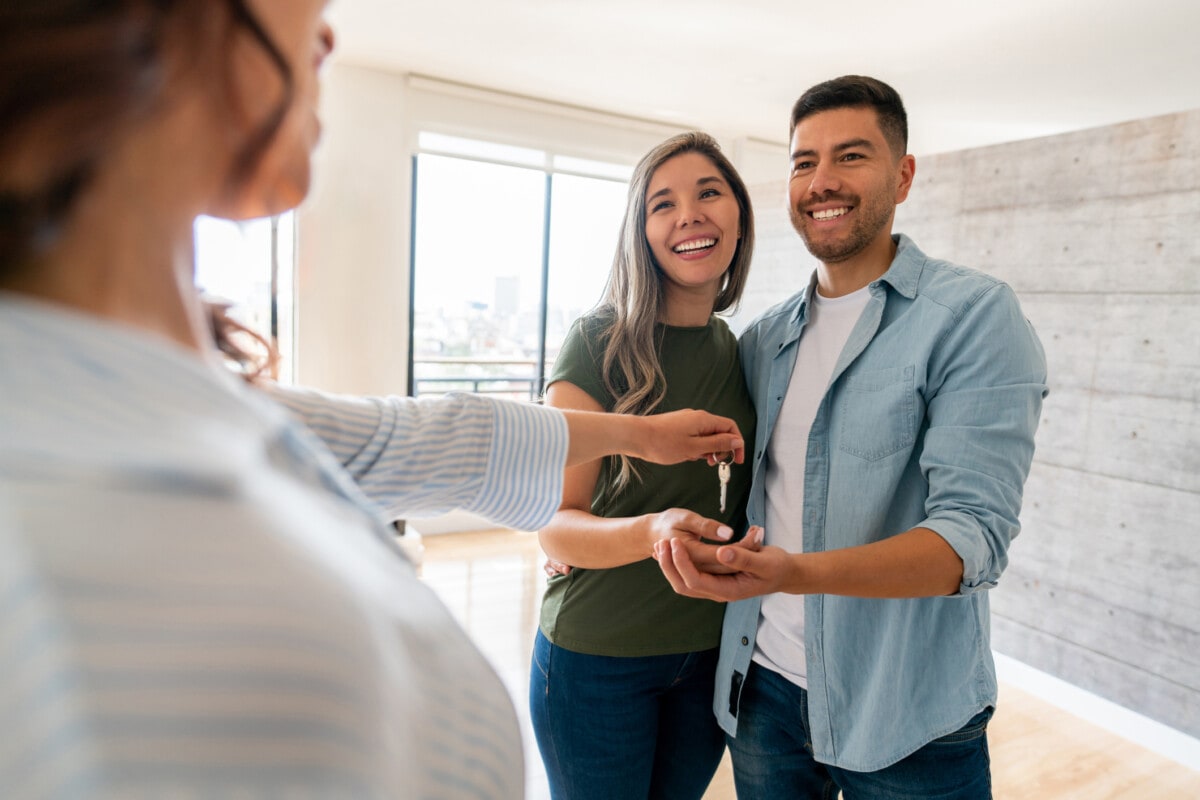 Real estate agent giving the keys of their new house to a happy couple