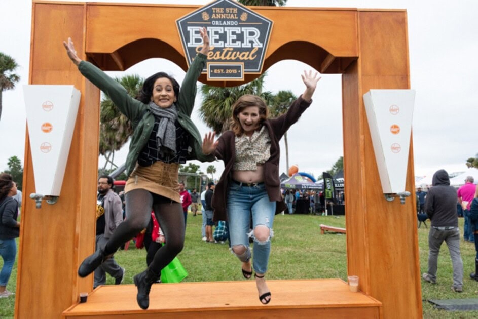 Two women jumping off Beer Festival photo backdrop