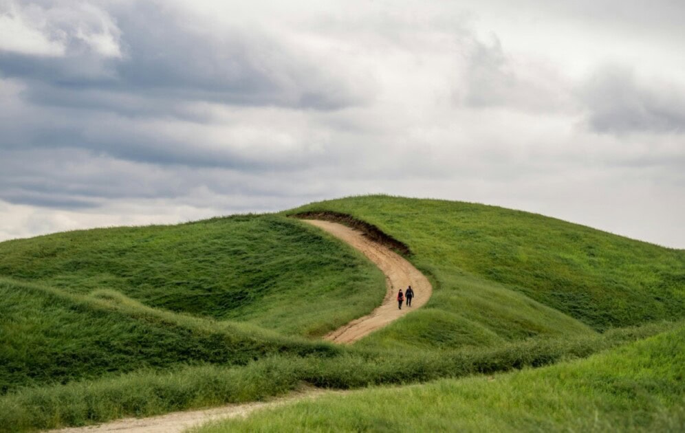 Two people walking up a dirt trail