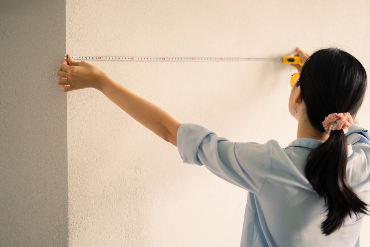 woman measuring square feet of house