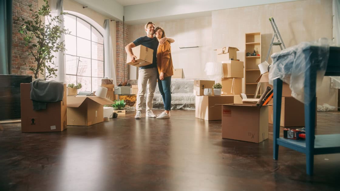 A couple stands proudly in the house they just bought.