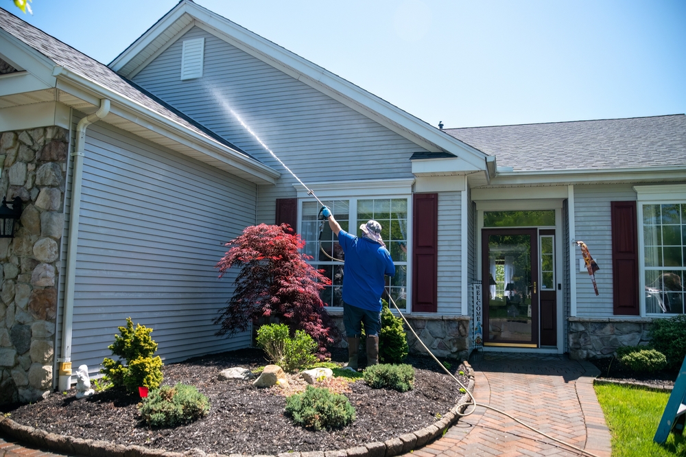 a man outside powerwashing a house