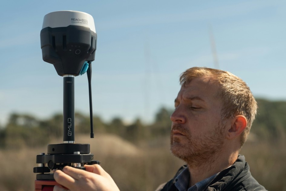 a ginger man surveys his land with a device before decided to install a rainwater harvesting system per Redfin's recommendation